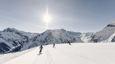 Drei Skifahrer fahren eine breite, frisch präparierte Piste in Gargellen bei Sonnenschein mit Bergpanorama im Hintergrund. | © Gargellner Bergbahnen GmbH & Co KG, Daniel Zangerl