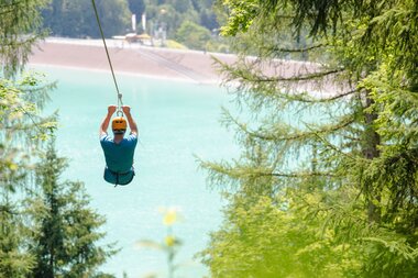 Ein Junge der mit einem 565 m langen Stahlseil befestigt über das Staubecken Latschau fliegt | © Golm Silvretta Lünersee Tourismus GmbH Bregenz, Stefan Kothner