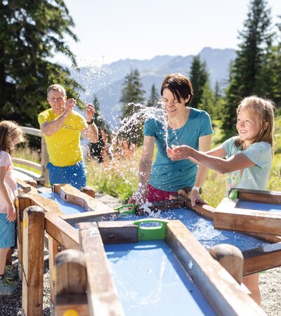 Golmis Forschungspfad am Erlebnisberg Golm | © Golm Silvretta Lünersee Tourismus GmbH Bregenz, Stefan Kothner Vater und Mutter, die gemeinsam mit ihren zwei Töchtern beim Wasserspiel auf Golmis Forschungspfad die Kraft des Wassers entdecken | © Golm Silvretta Lünersee Tourismus GmbH Bregenz, Stefan Kothner